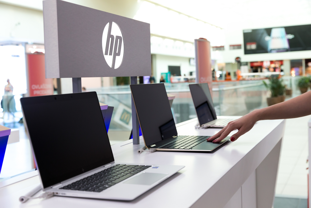 Bancada com diversos notebooks da HP, com o logo da companhia atrás