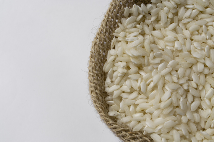 Rustic cloth bag to the right of the image, containing grains of raw arboreal rice