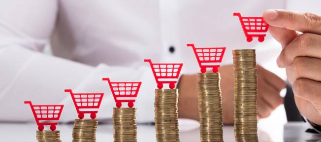 Businessperson placing shopping cart over stacked coins