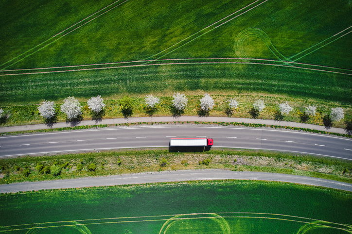 Drone shot direct above a truck moves along a single road.