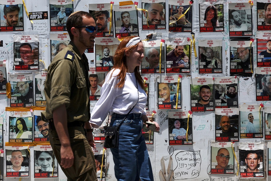 Casal passa por cartazes de reféns sequestrados durante o ataque de 7 de outubro a Israel pelo Hamas (REUTERS/Shannon Stapleton)
