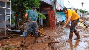 Moradores tentam limpar a sujeira e retirar a lama em região afetada pelas enchentes no Rio Grande do Sul (Foto: Gustavo Mansur/Palácio Piratini)