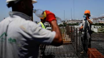 Operários da construção bebem água enquanto trabalham em obra em meio a forte calor em Pristina, no Kosovo (REUTERS/Valdrin Xhemaj)