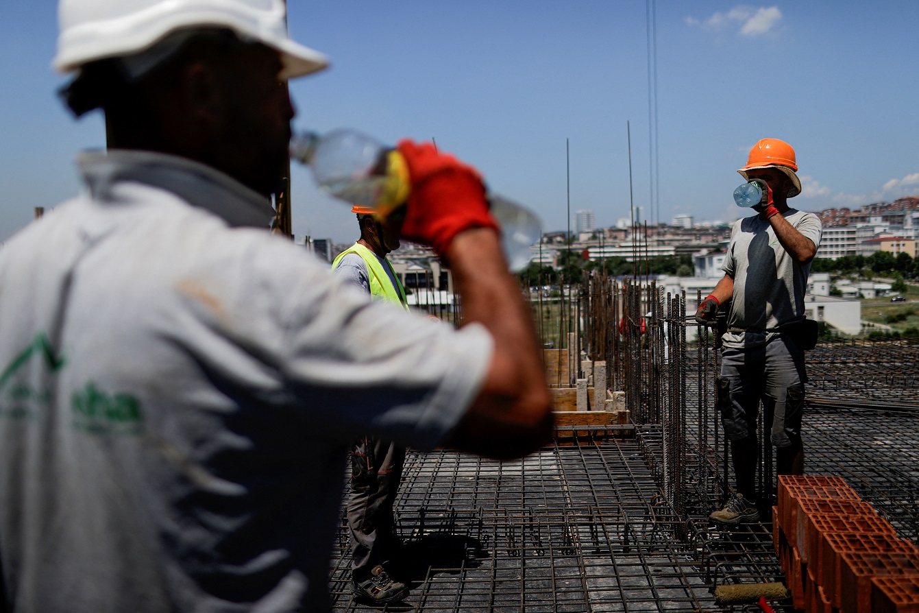 Operários da construção bebem água enquanto trabalham em obra em meio a forte calor em Pristina, no Kosovo (REUTERS/Valdrin Xhemaj)
