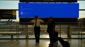 Funcionários da United Airlines aguardam ao lado de um monitor de partidas exibindo uma tela azul de erro, também conhecida como "Tela Azul da Morte", dentro do Terminal C no Aeroporto Internacional de Newark, após a United Airlines e outras companhias aéreas cancelarem voos devido a uma interrupção tecnológica em todo o mundo causada por uma atualização do software "Falcon Sensor" da Crowdstrike, que causou a falha nos sistemas Microsoft Windows, em Newark, Nova Jersey, EUA, em 19 de julho de 2024. REUTERS/Bing Guan
