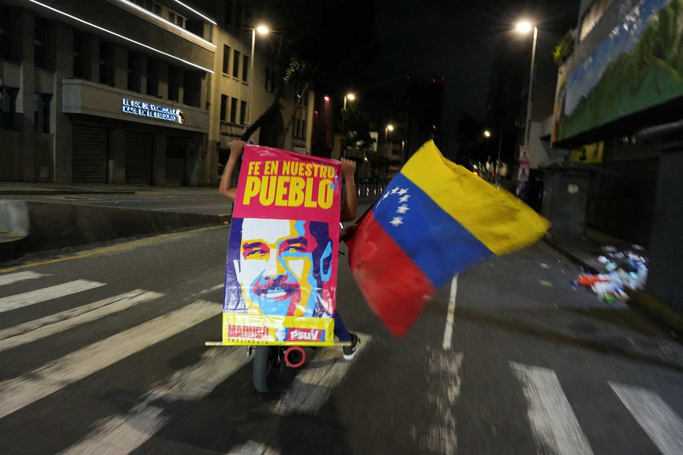 Apoiadores carregando bandeira e cartaz com o presidente venezuelano Nicolás Maduro comemoram em Caracas - 
29/07/2024 (Foto: Alexandre Meneghini/Reuters)