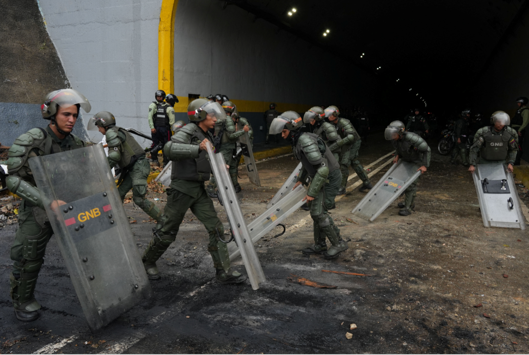 Membros da Guarda Nacional Bolivariana da Venezuela usam seus escudos após um protesto de apoiadores da oposição venezuelana (Foto: Alexandre Meneghini Reuters)