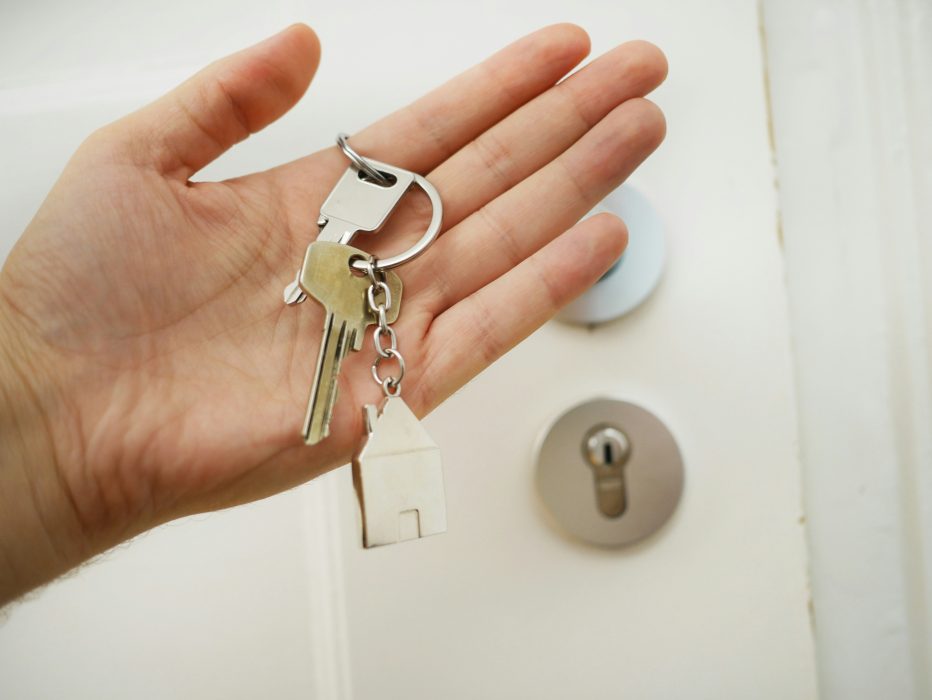 Mão segurando uma chave com uma porta atrás