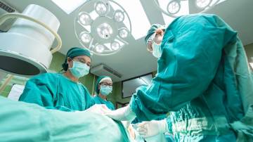 Equipe médica com três profissionais realiza cirurgia em hospital