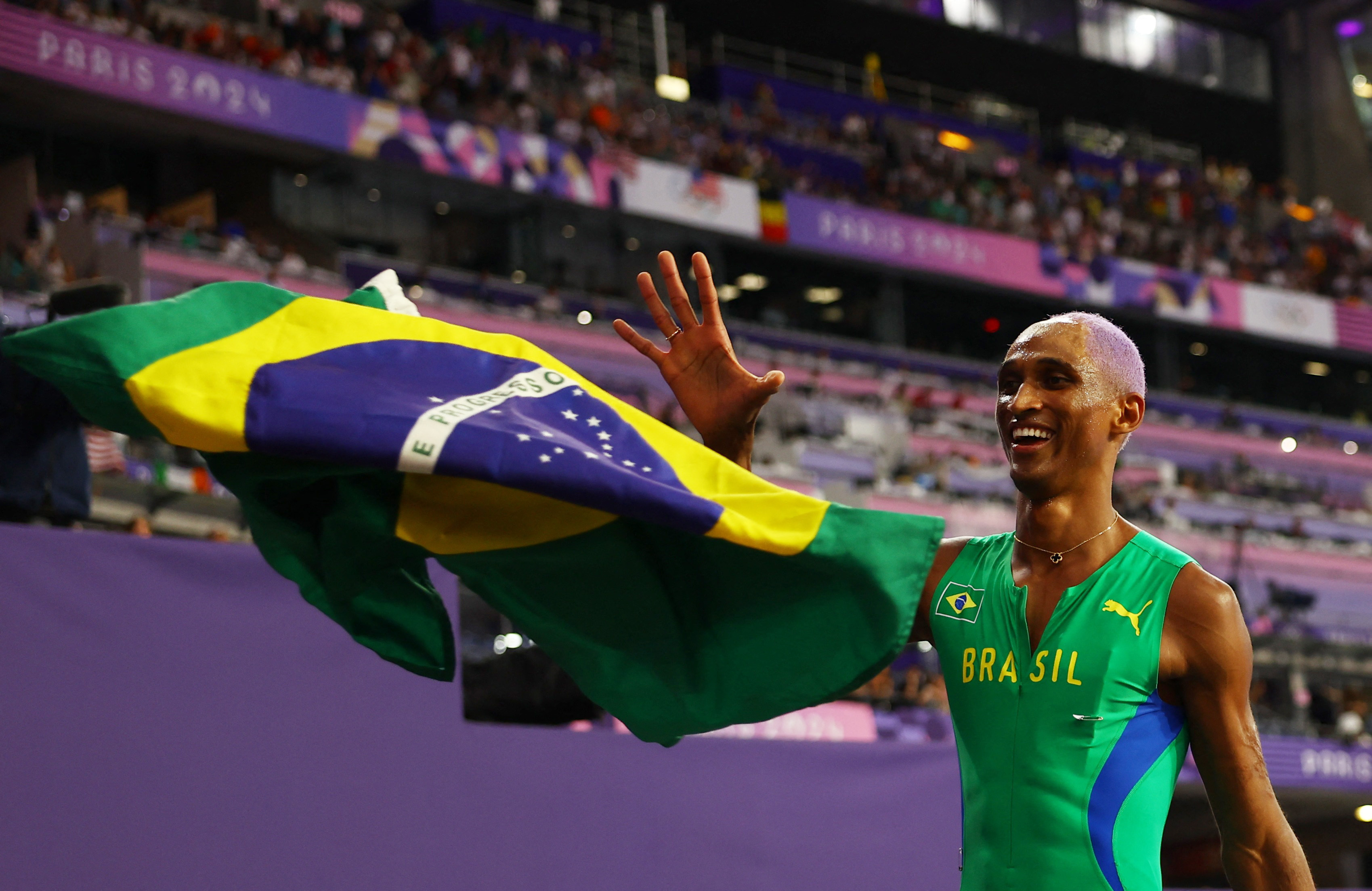 Alison dos Santos celebra com a bandeira do Brasil após conquistar o bronze (REUTERS/Kai Pfaffenbach)