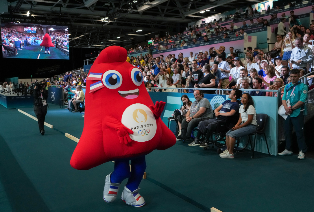 Phryge, o mascote das Olimpíadas de Paris, acena para os espectadores durante uma partida de handebol feminino entre Brasil e Espanha na South Paris Arena durante os Jogos Olímpicos de 2024 em Paris, 25 de julho de 2024. (Chang W. Lee/The New York Times)