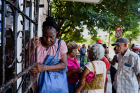 Mulher se segura em uma cerca ao sair de um comércio em Havana