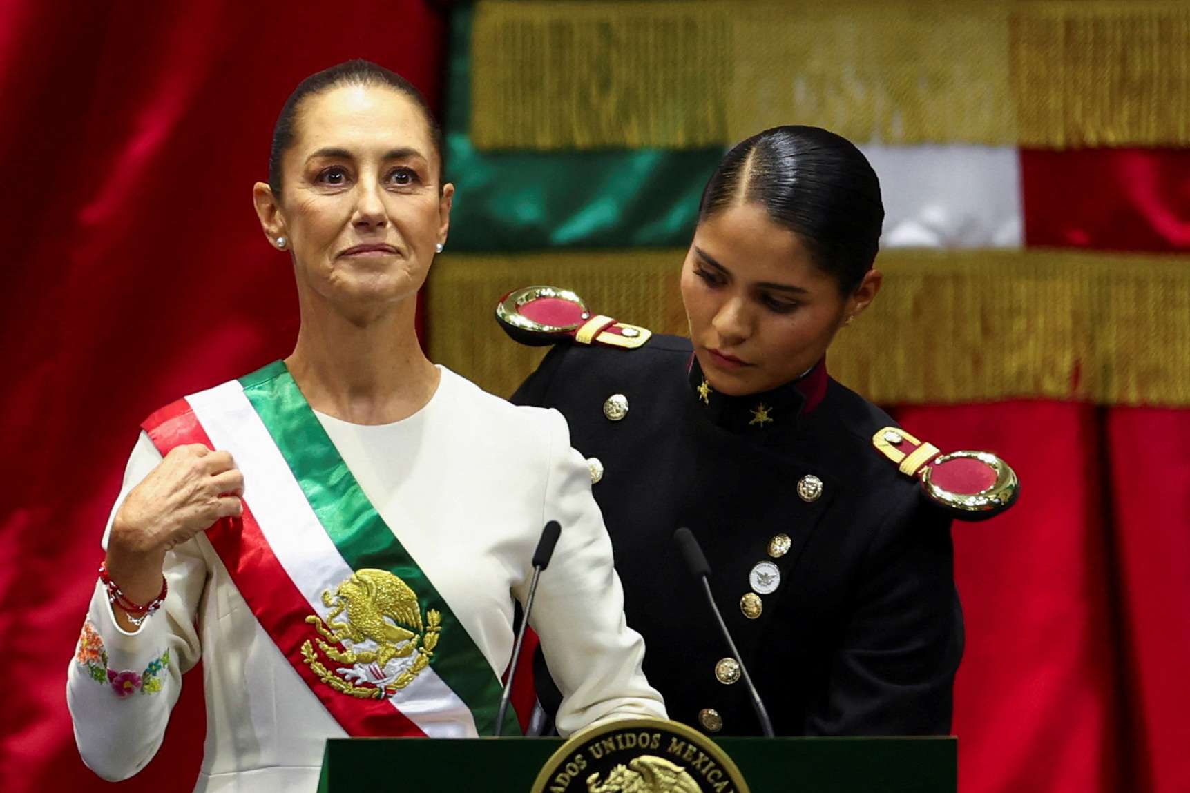 A nova presidente do México, Claudia Sheinbaum, é auxiliada ao colocar a faixa durante sua cerimônia de posse - 01/10/2024 (Foto: Raquel Cunha/Reuters)