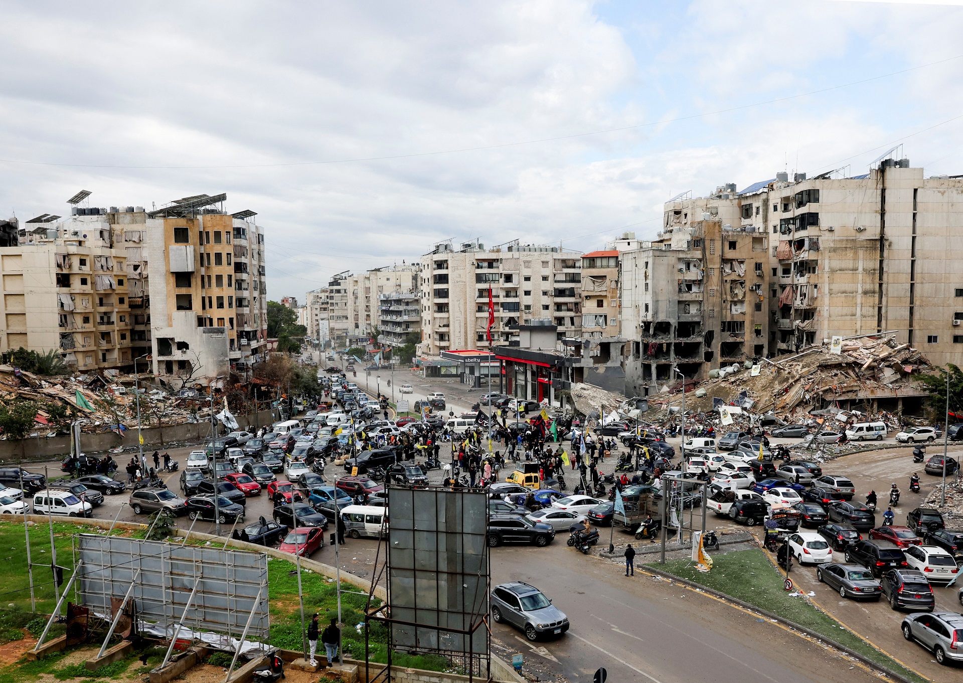 Pessoas se reúnem enquanto veículos passam perto de prédios danificados, nos subúrbios ao sul de Beirute, após um cessar-fogo entre Israel e o Hezbollah entrar em vigor, Líbano, 27 de novembro de 2024. REUTERS/Mohamed Azakir