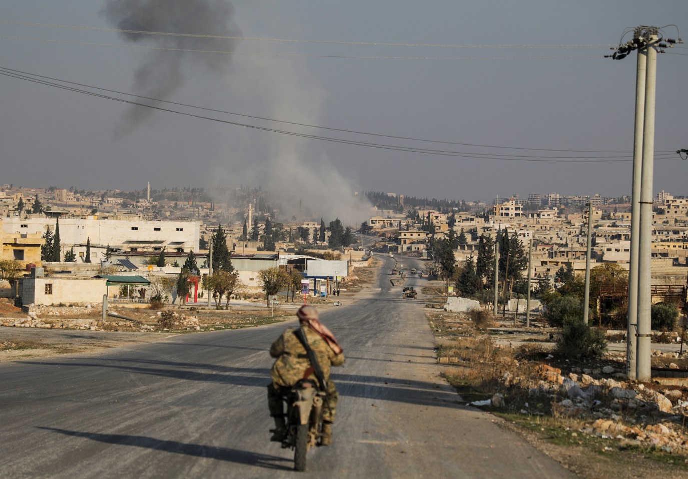 A fumaça sobe enquanto um membro dos rebeldes liderados pelo grupo militante islâmico Hayat Tahrir al-Sham dirige uma motocicleta em al-Rashideen, província de Aleppo, Síria, em 29 de novembro de 2024. REUTERS/Mahmoud Hasano.

