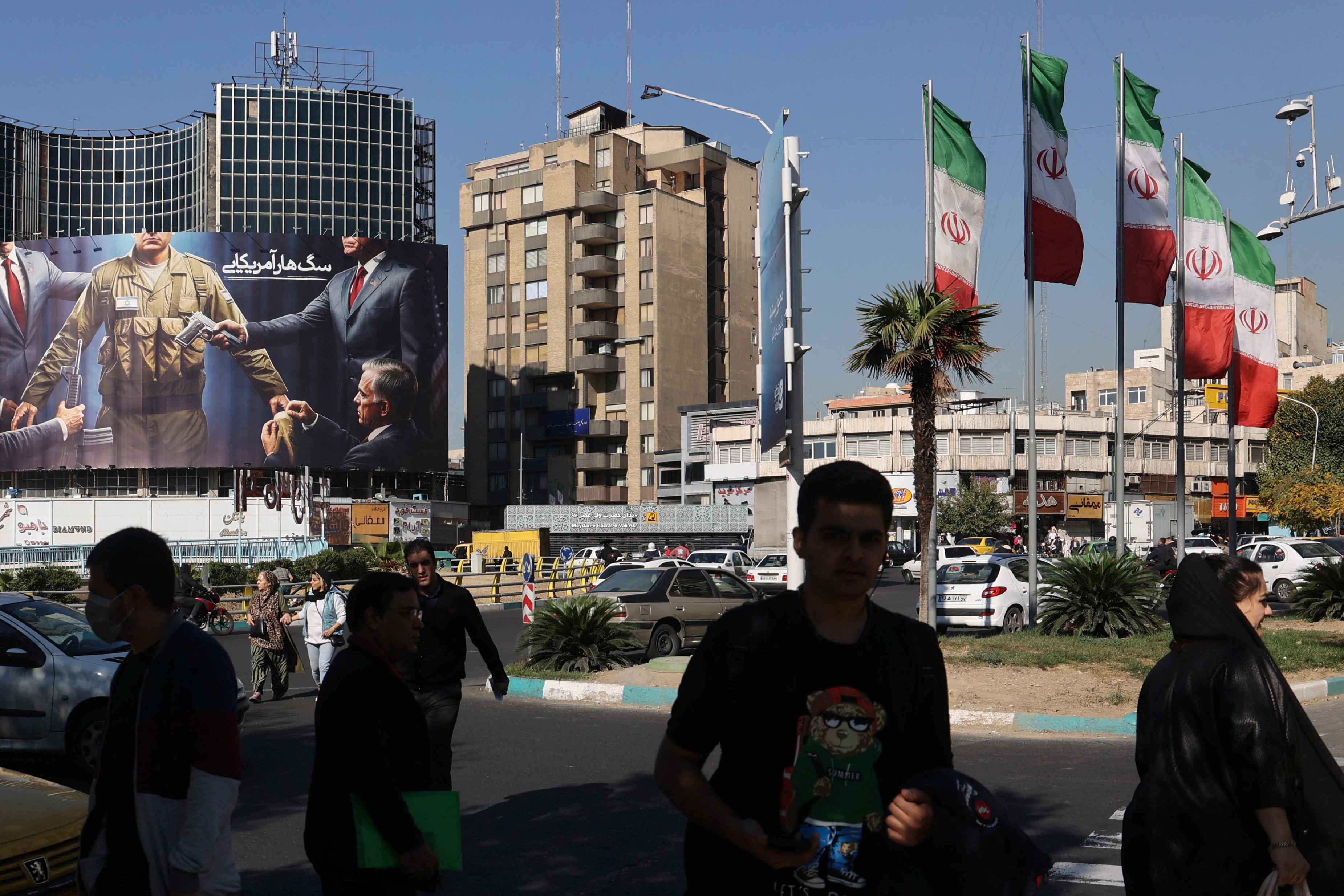 Iranianos caminham ao lado de um outdoor anti-EUA e anti-Israel em uma rua em Teerã, Irã, em 6 de novembro de 2024. Majid Asgaripour/WANA (West Asia News Agency) via REUTERS