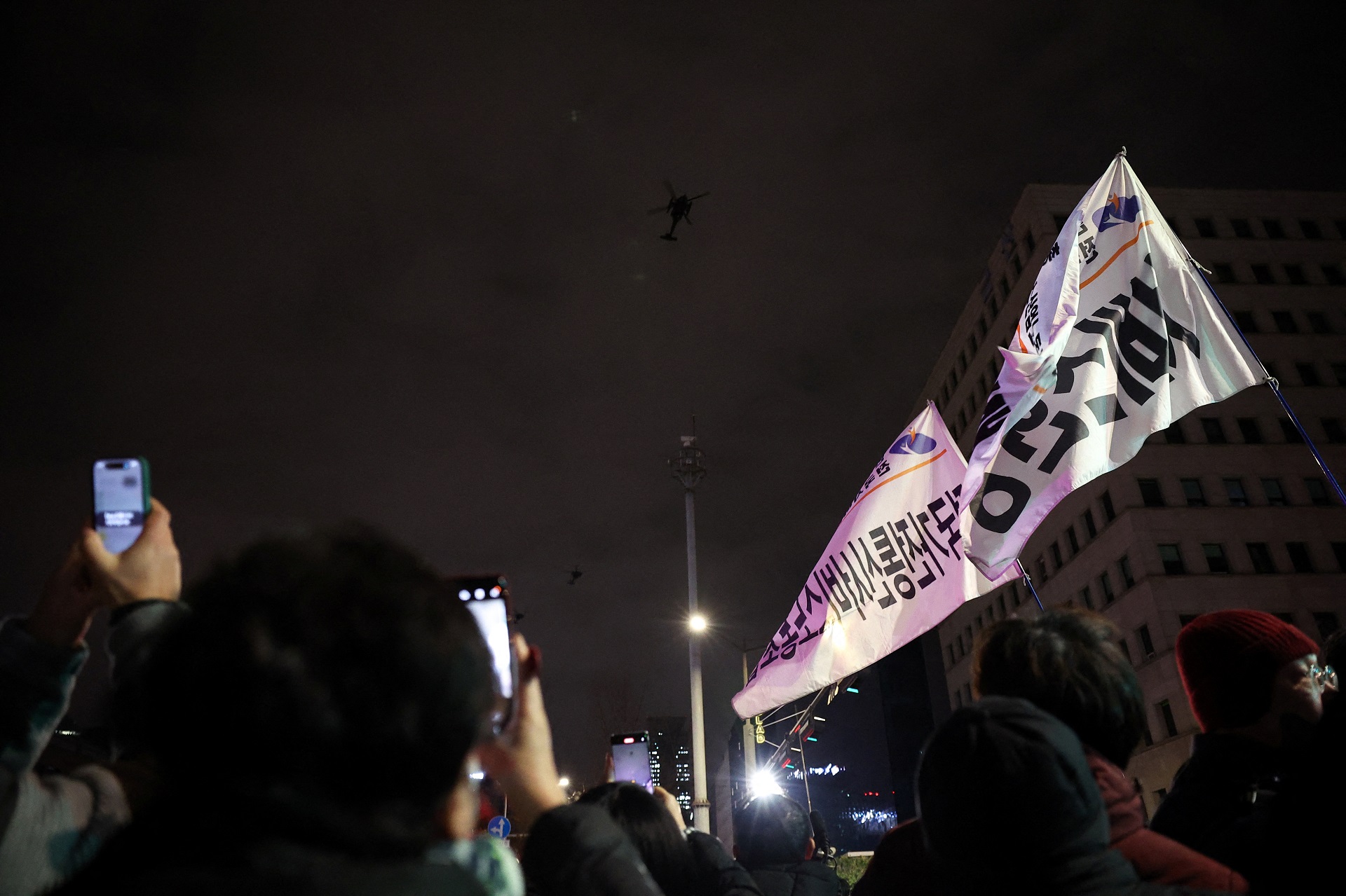 Pessoas agitam faixas enquanto helicópteros militares voam, depois que o presidente sul-coreano Yoon Suk Yeol declarou lei marcial, em Seul, Coreia do Sul, em 4 de dezembro de 2024. REUTERS/Kim Hong-Ji