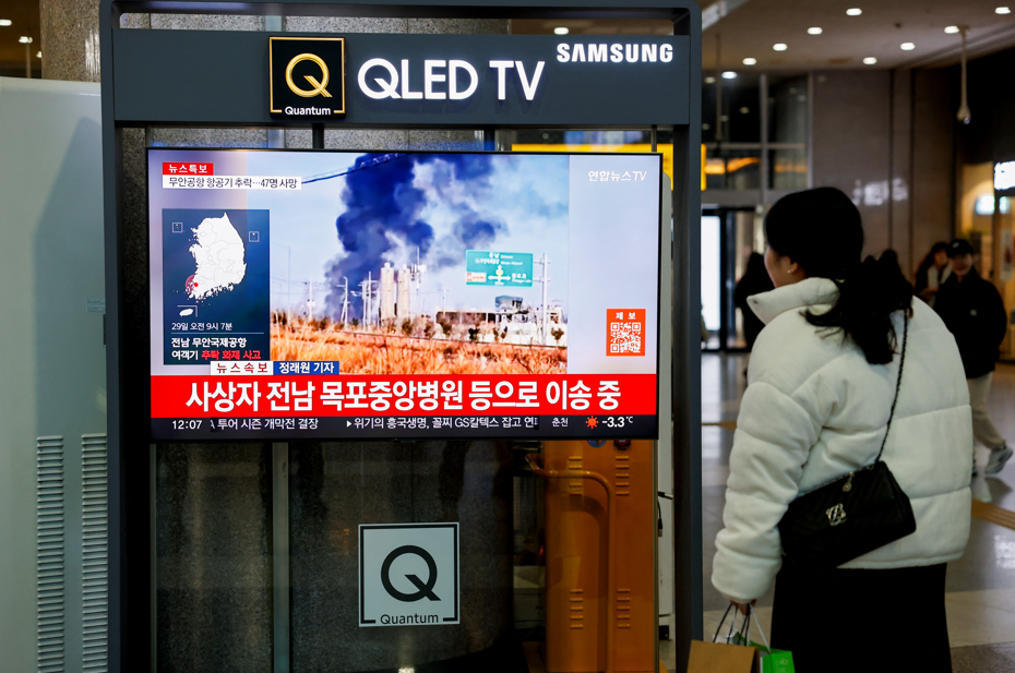 Uma mulher assiste a uma TV transmitindo imagens do acidente de aeronave no Aeroporto Internacional de Muan