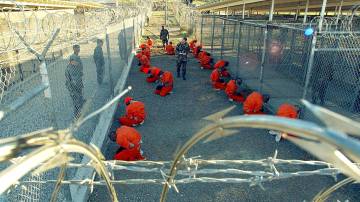 Foto tirada pelas forças armadas dos EUA em 11 de janeiro de 2002, mostrando os primeiros prisioneiros na Baía de Guantánamo, Cuba, logo após sua chegada (Primeiro Oficial de Classe Shane T. McCoy/Marinha dos EUA)