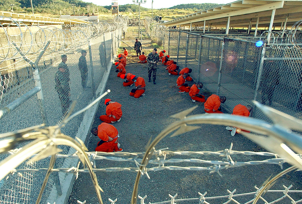 Foto tirada pelas forças armadas dos EUA em 11 de janeiro de 2002, mostrando os primeiros prisioneiros na Baía de Guantánamo, Cuba, logo após sua chegada (Primeiro Oficial de Classe Shane T. McCoy/Marinha dos EUA)