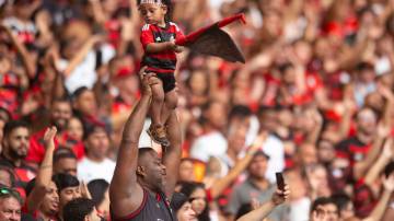 RIO DE JANEIRO, BRAZIL - DECEMBER 1: A supporter of Flamengo lifts a child during the match between Flamengo and Internacional at Maracana Stadium on December 1, 2024 in Rio de Janeiro, Brazil. (Photo by Max Peixoto/Eurasia Sport Images/Getty Images)